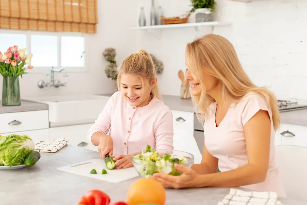Chef Maggie cooking with her daughter at home, both smiling and preparing a meal together.